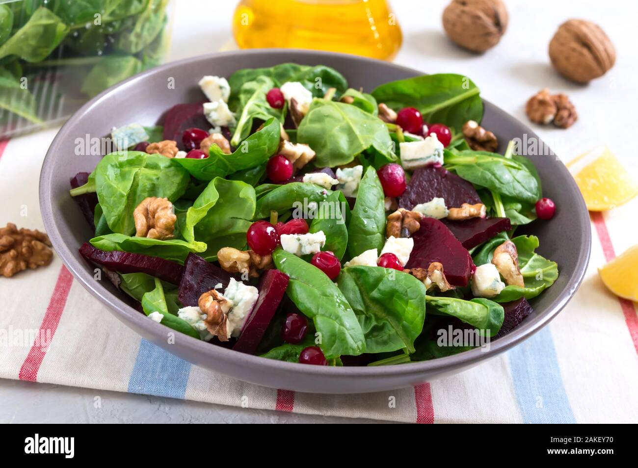Salad with young spinach, boiled beets, blue cheese, nuts, cranberries in a bowl on a light background. Tasty diet fitness dish. Vitamin salad. Proper Stock Photo