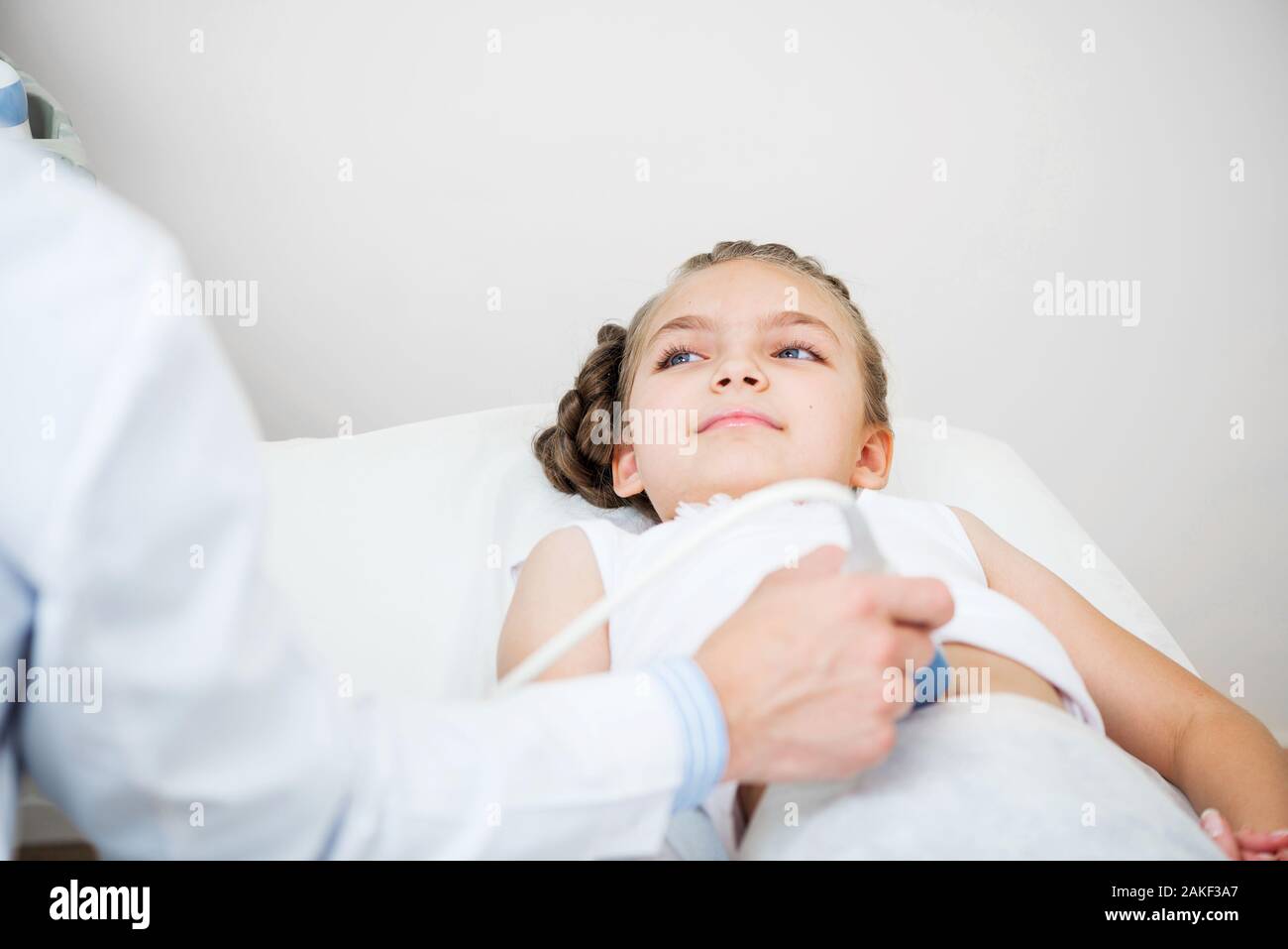 Sonographer moving transducer on belly of girl Stock Photo