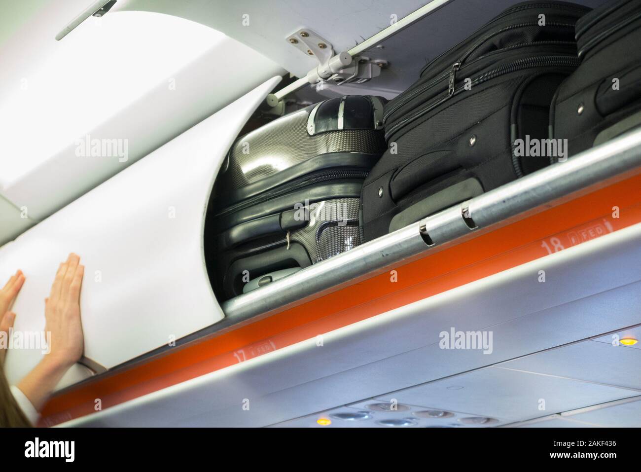 Cabin crew member closing and shutting the overhead passenger locker /  lockers / compartment / compartments for stowing passengers bags cabin  luggage on an Easyjey Airbus A320 or A319 plane. (115 Stock Photo - Alamy