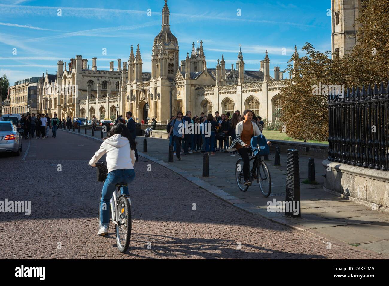 Oxbridge university, view of university students cycling in King's Parade with King's College ornate main gate visible in the distance, Cambridge, UK Stock Photo