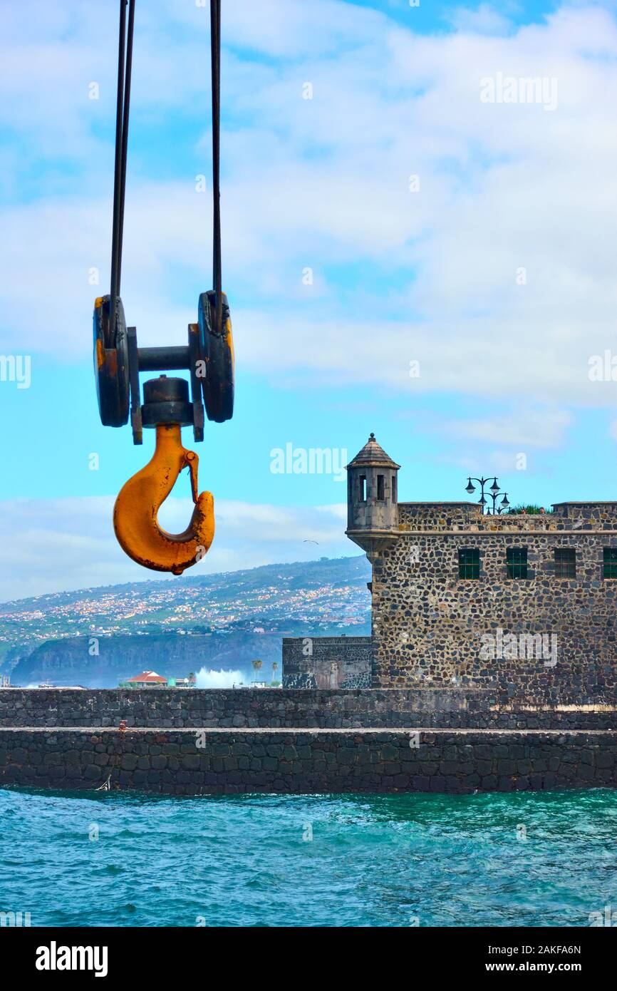 Port crane hook and fort Bateria de Santa Barbara at the harbour of Puerto de la Cruz town, Tenerife, Canary Islands Stock Photo