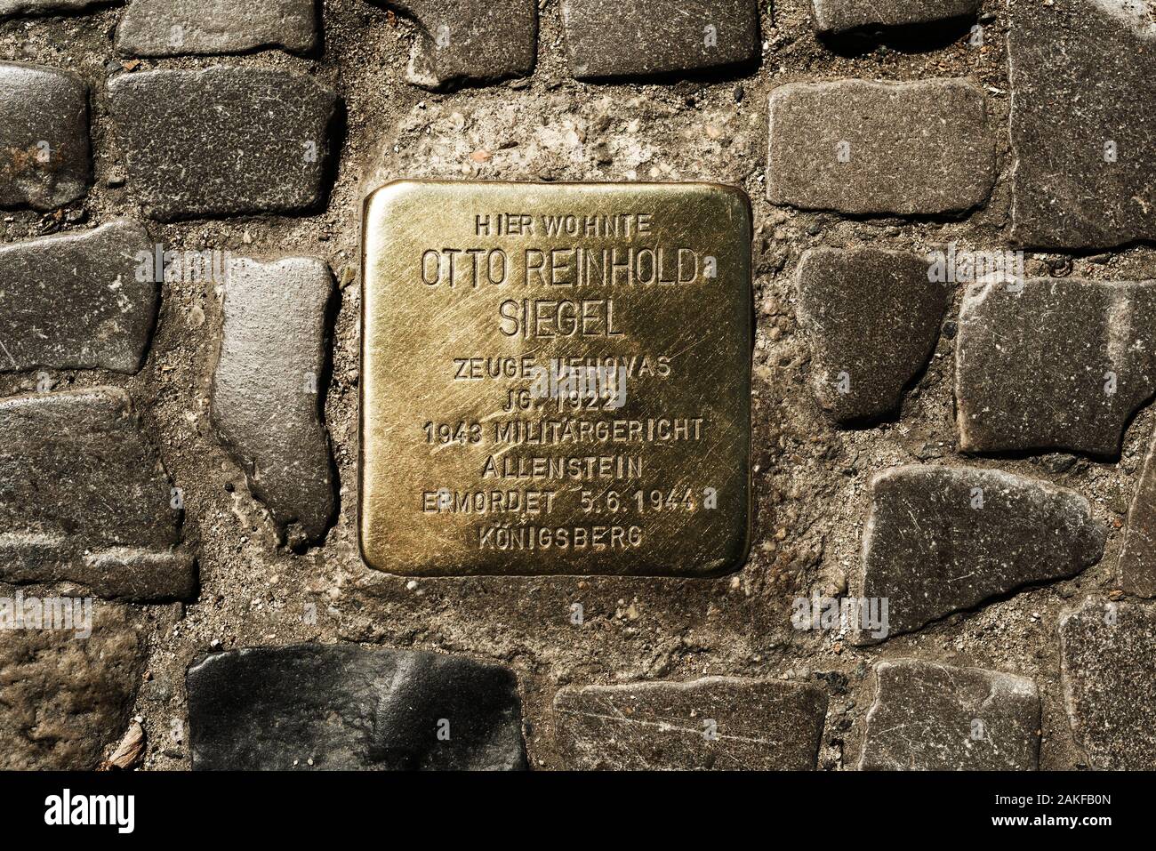 BERLIN, GERMANY - MAY 24, 2018: A Stolperstein, a golden cube with the name and life dates of a victim of nazi extermination, in the pavement of a str Stock Photo