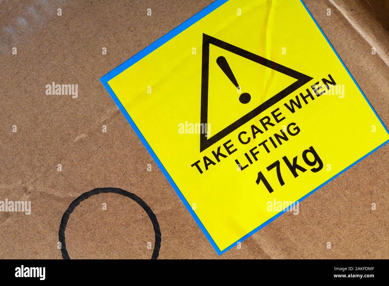 Take care when lifting 17kg yellow sticker label stuck on cardboard box Stock Photo