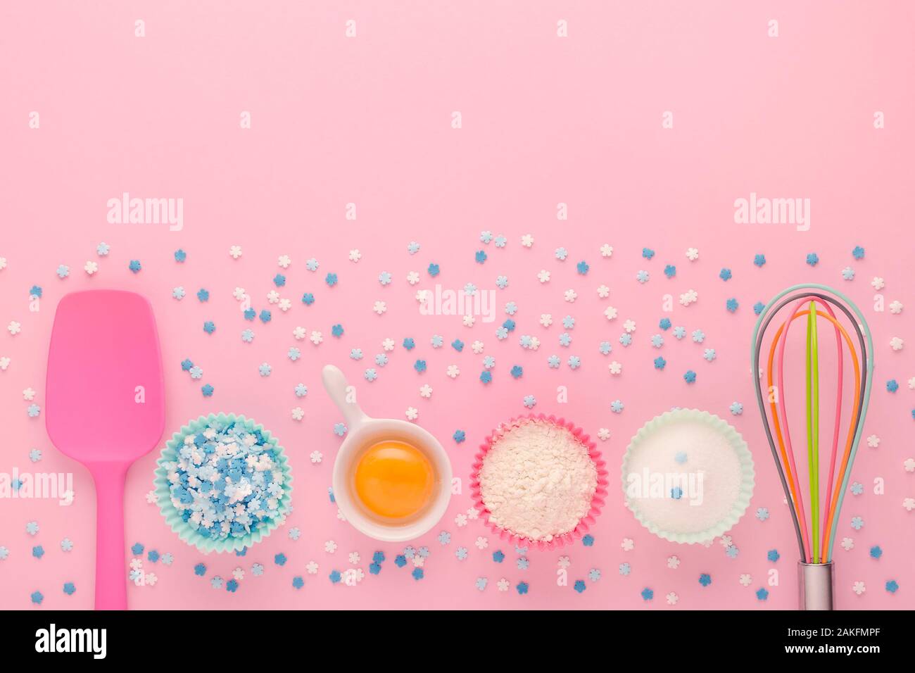 baking ingredients, egg, flour, sugar, sweet decoration and kitchen tools on pink background Stock Photo