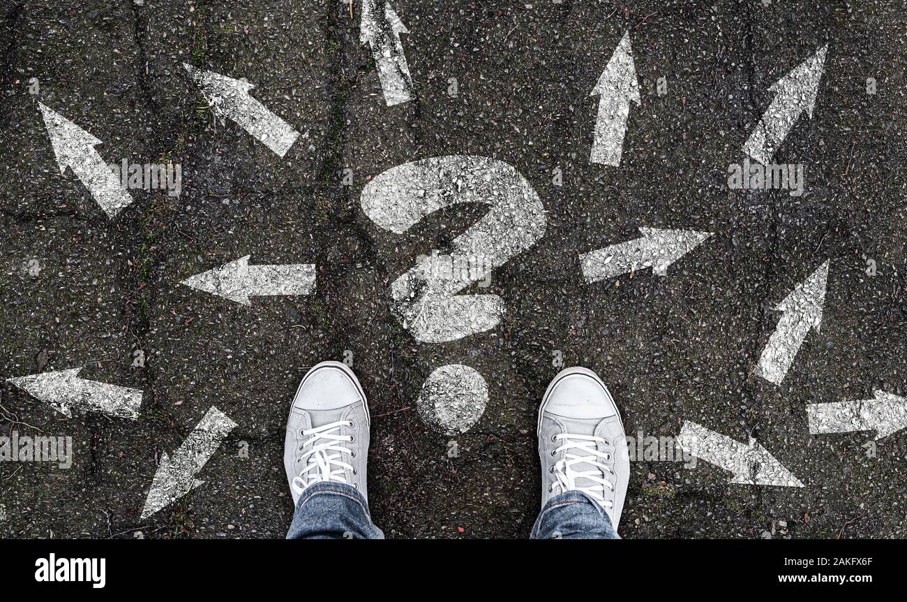 person standing on road with question mark and arrow markings pointing in different directions, decision making concept Stock Photo