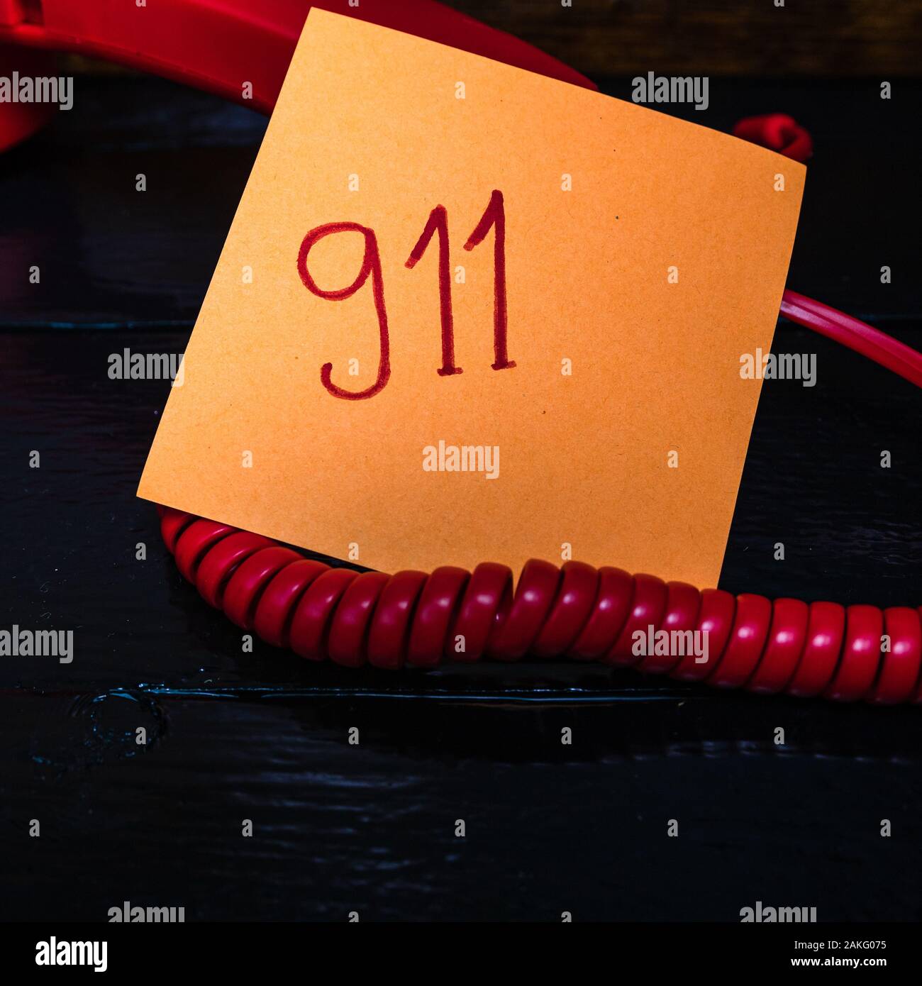 Writing 911 on memo post reminder. sticky paper surrounded by wire of
