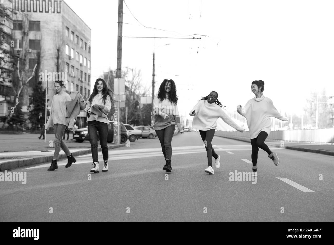 Multiracial group of friends from five young women runs and has a fun on city street. The concept of friendship and unity between different human race Stock Photo