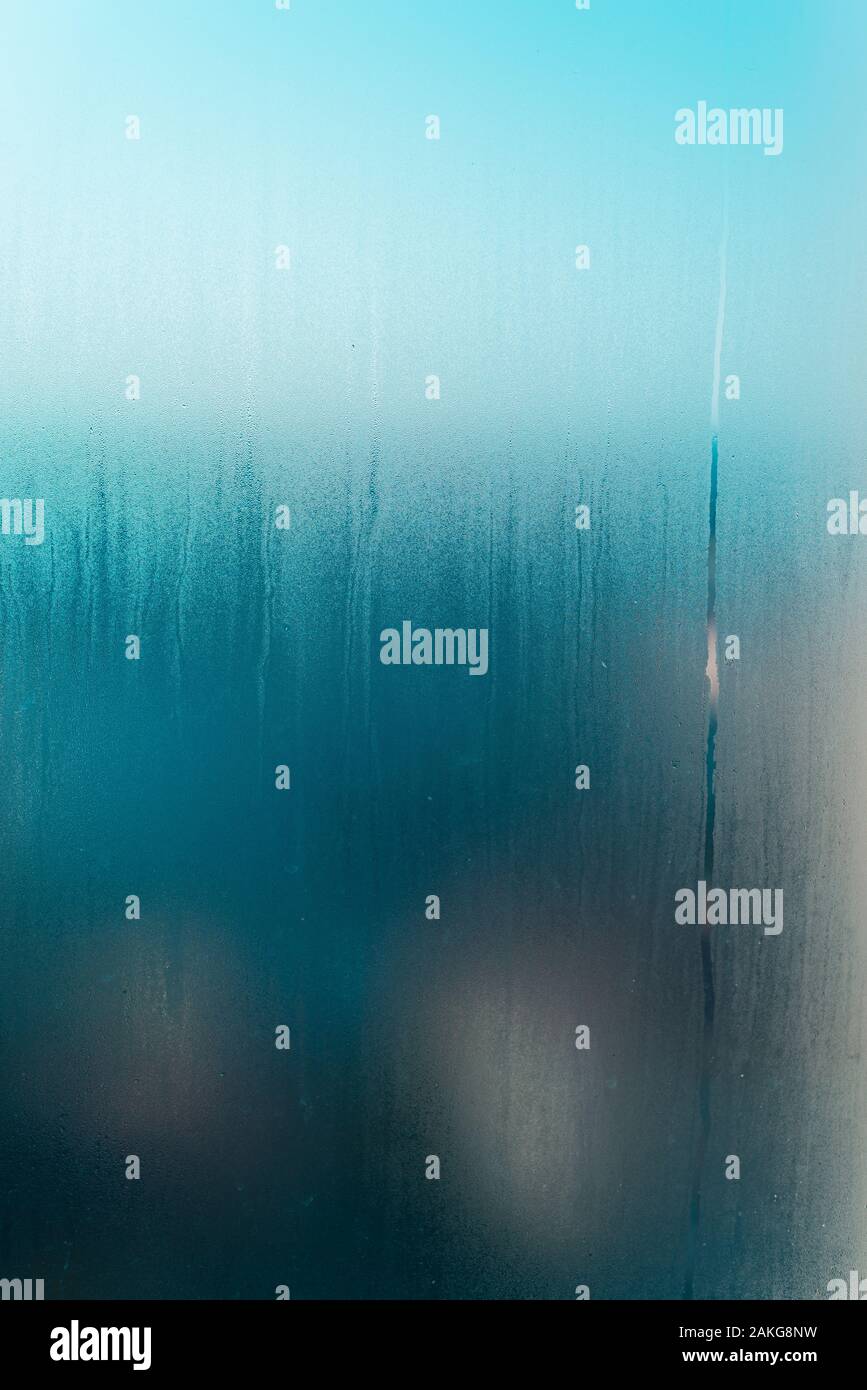 Condensation on a frosted window glass in winter background vertical