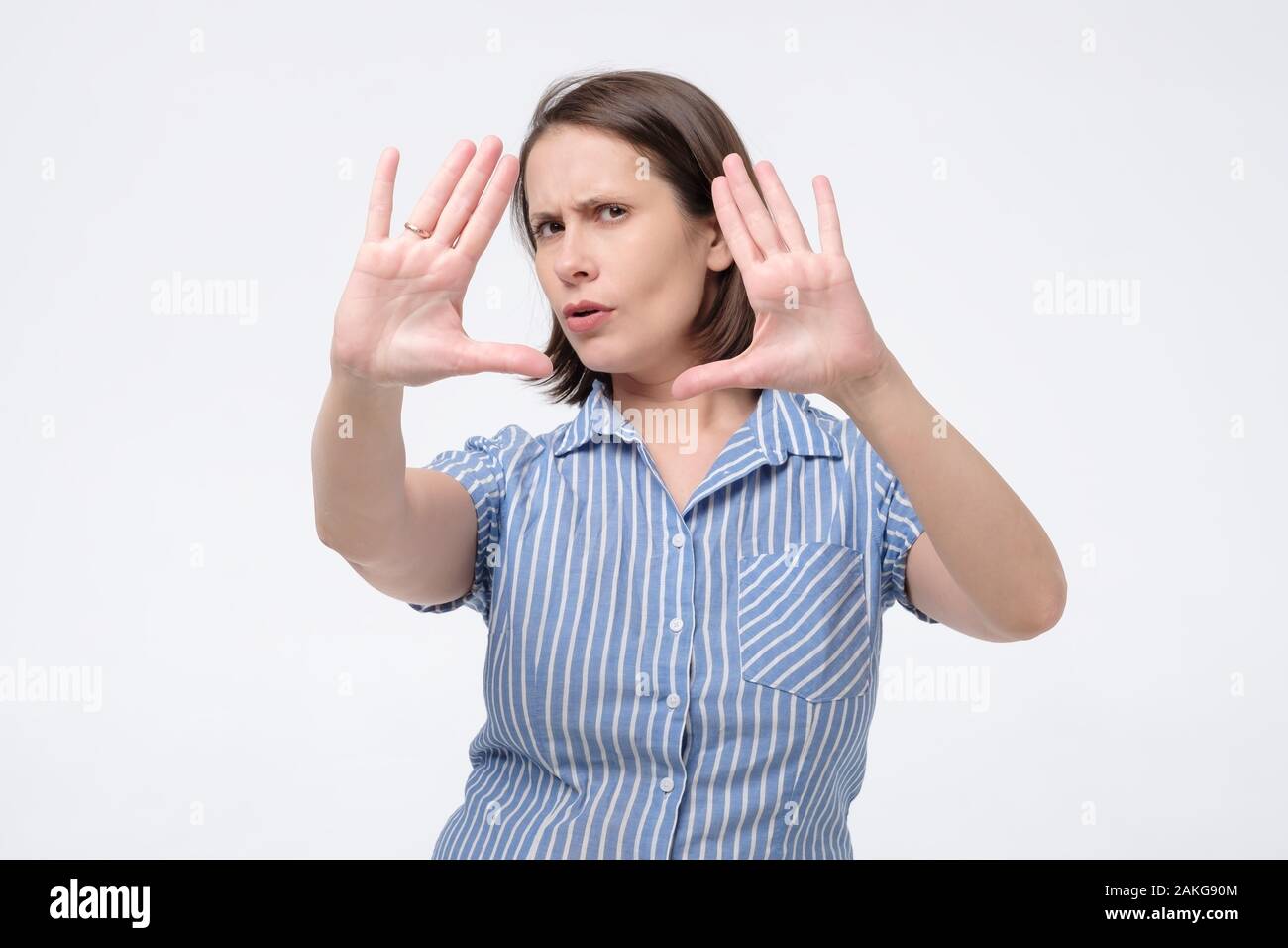 Mature caucasian female teacher or office manager pushing hands refusing or defending herself. Studio shot Stock Photo