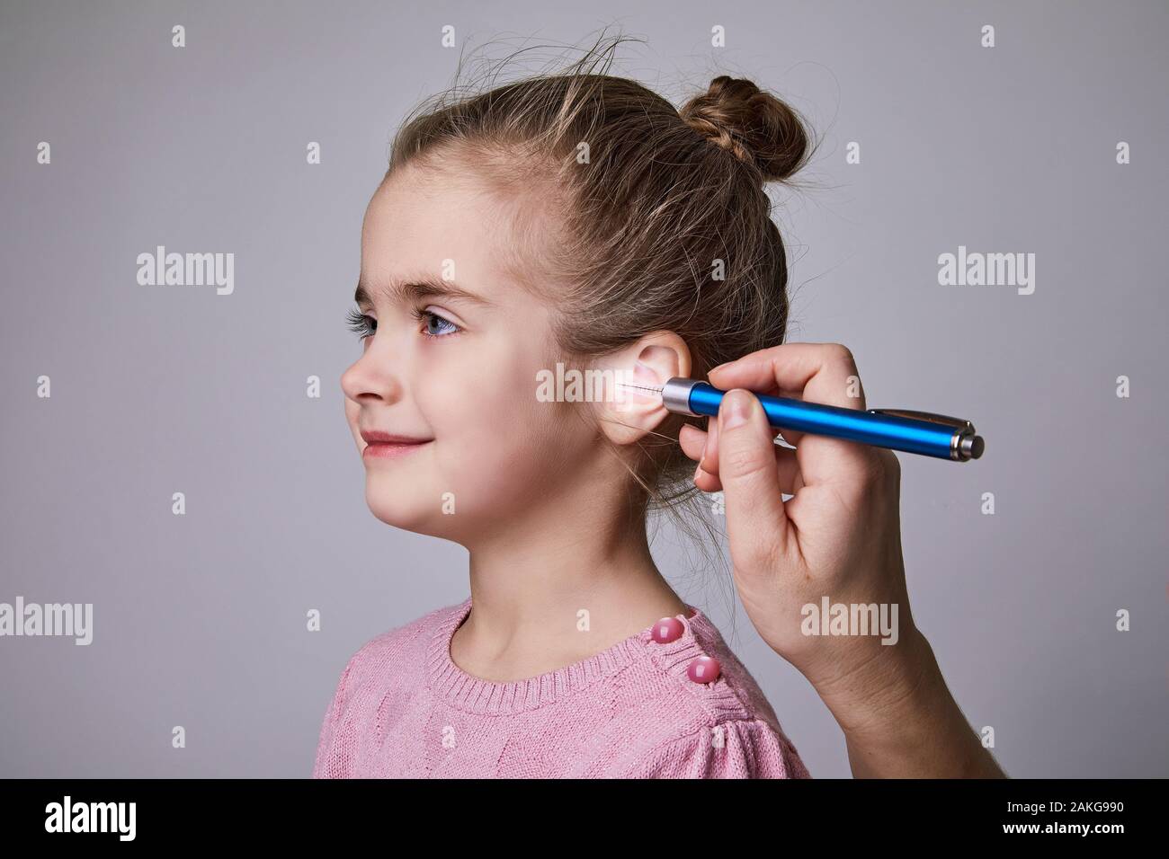 Doctor Examining Girl's Ear With Medical flashlight pen. Audiologist