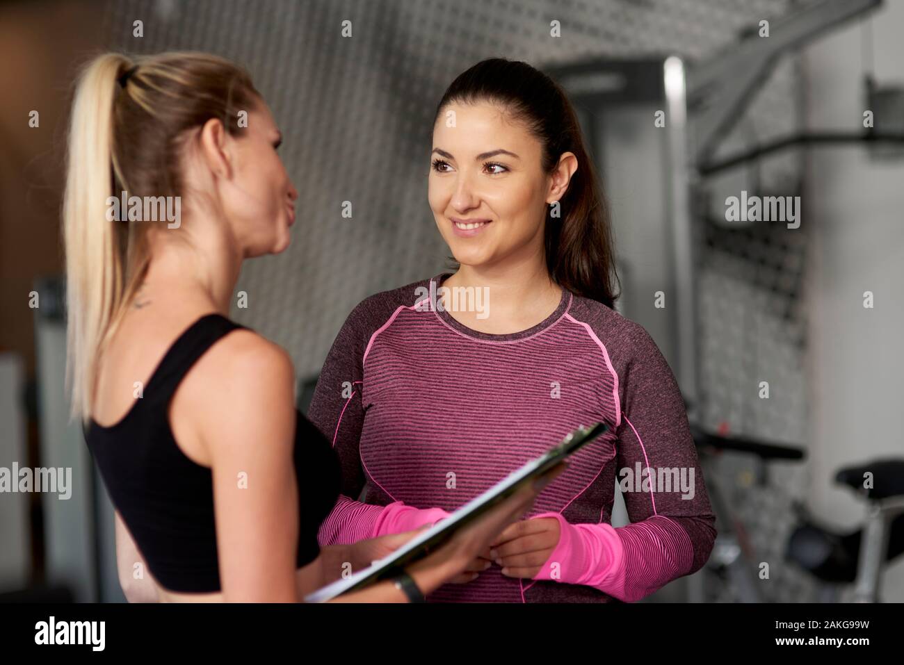 Personal trainer guding young woman at gym Stock Photo