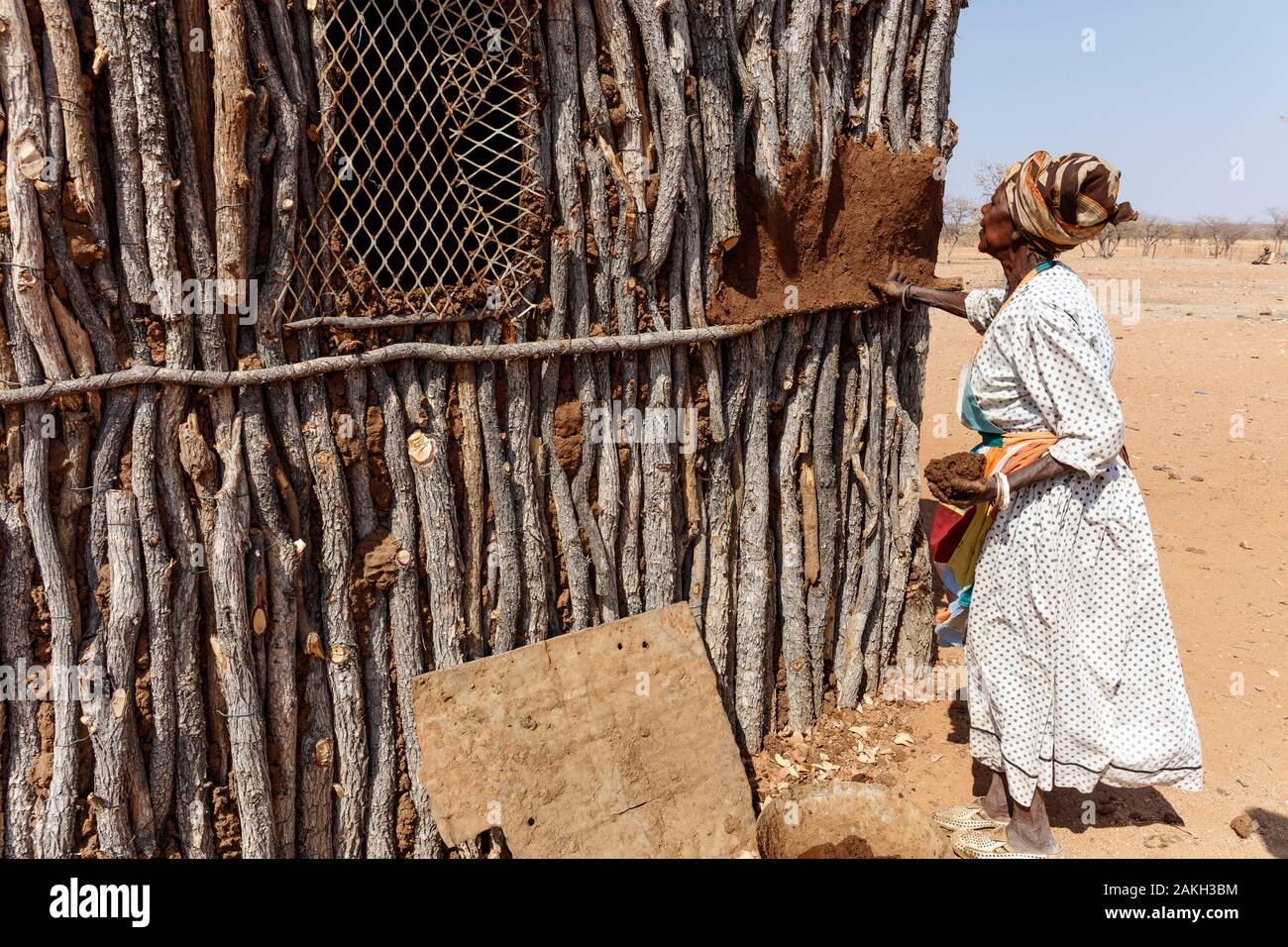Namibia, Kunene province, Kamanjab, a Damara woman coating her house walls with cob Stock Photo