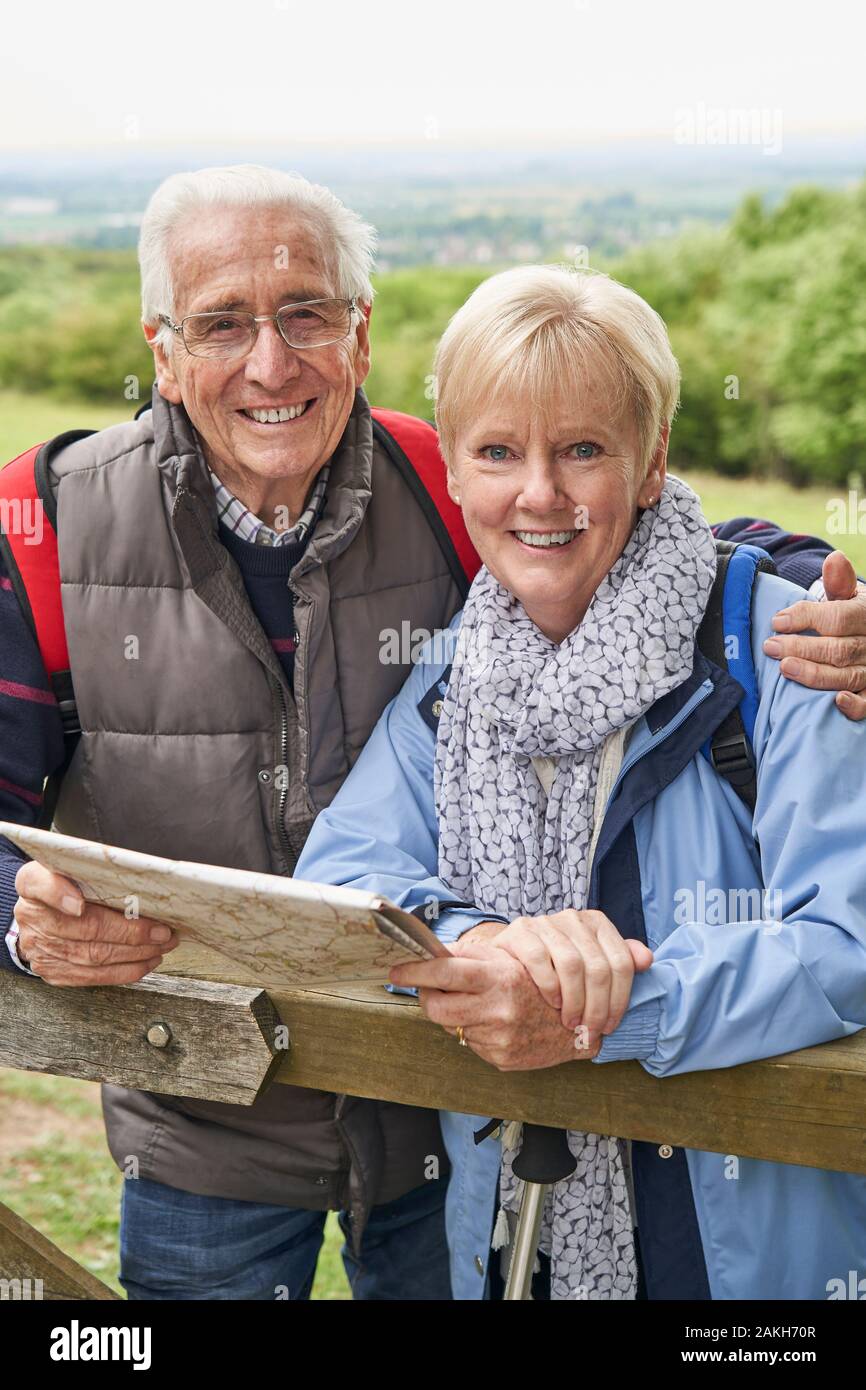 Portrait Of Retired Couple On Walking Holiday Resting On Gate With Map Stock Photo