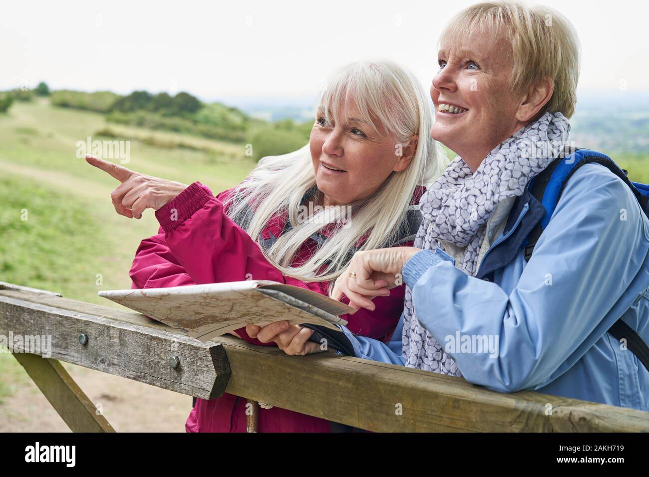 Two Senior Women Friends On Walking Holiday Resting On Gate With Map Stock Photo