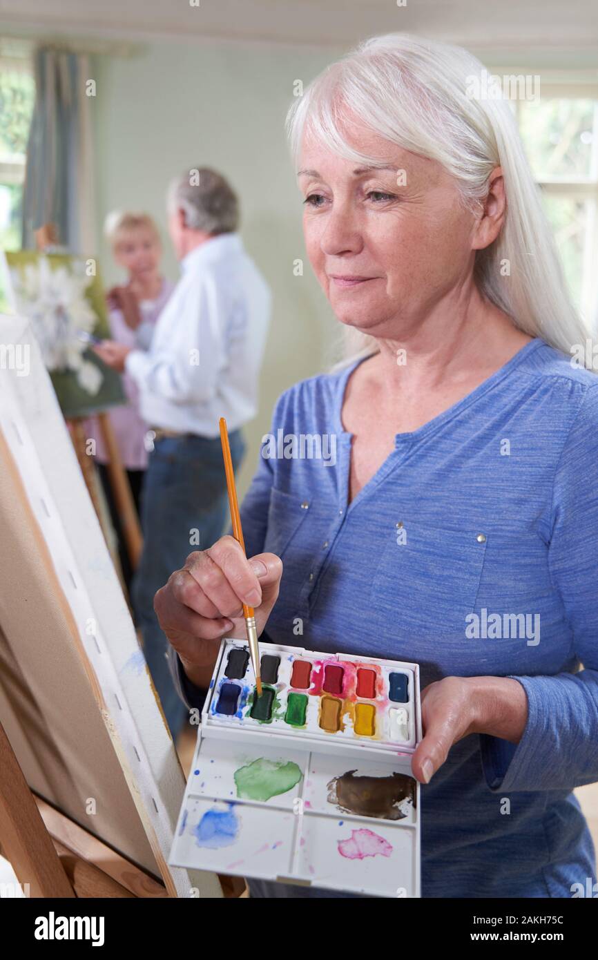 Senior Woman Attending Painting Class With Teacher In Background Stock Photo