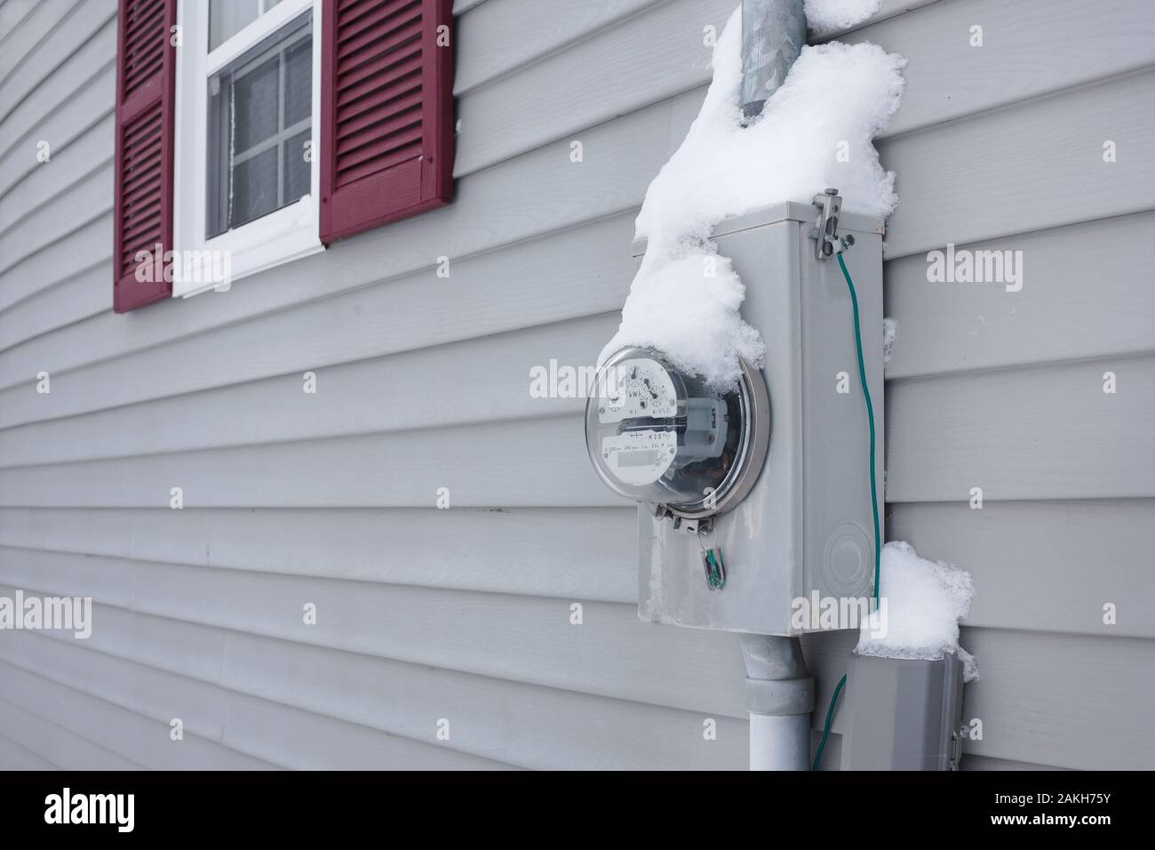 Frozen electrical utility meter on house exterior siding Stock Photo