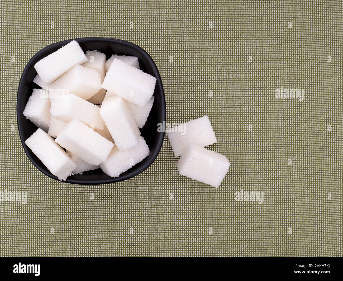 White refined sugar lumps, cubes, in bowl on fabric background with copyspace. Stock Photo