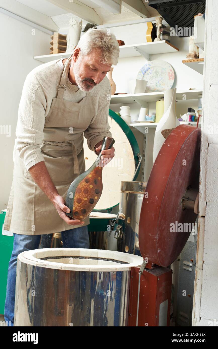 Mature  Man In Pottery Studio Firing Vase In Kiln Stock Photo