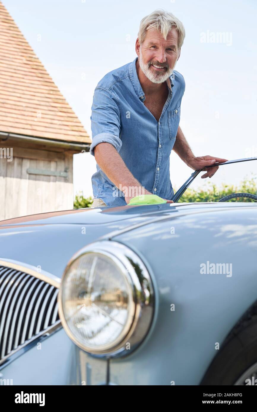 Portrait Of Mature Man Polishing Restored Classic Sports Car Outdoors At Home Stock Photo