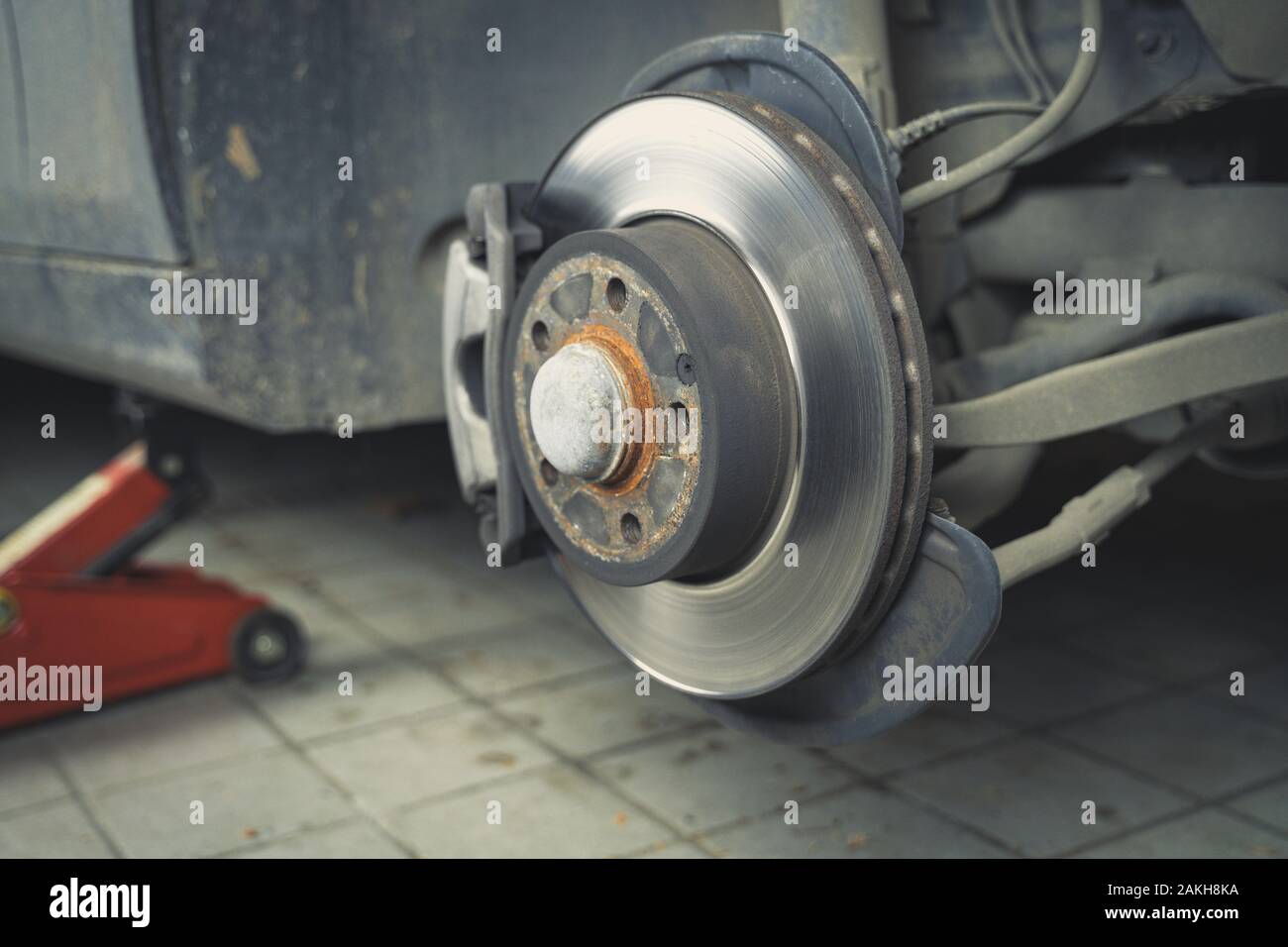 Car without wheel and lift up by hydraulic, waiting for tire replacement in a garage. Stock Photo
