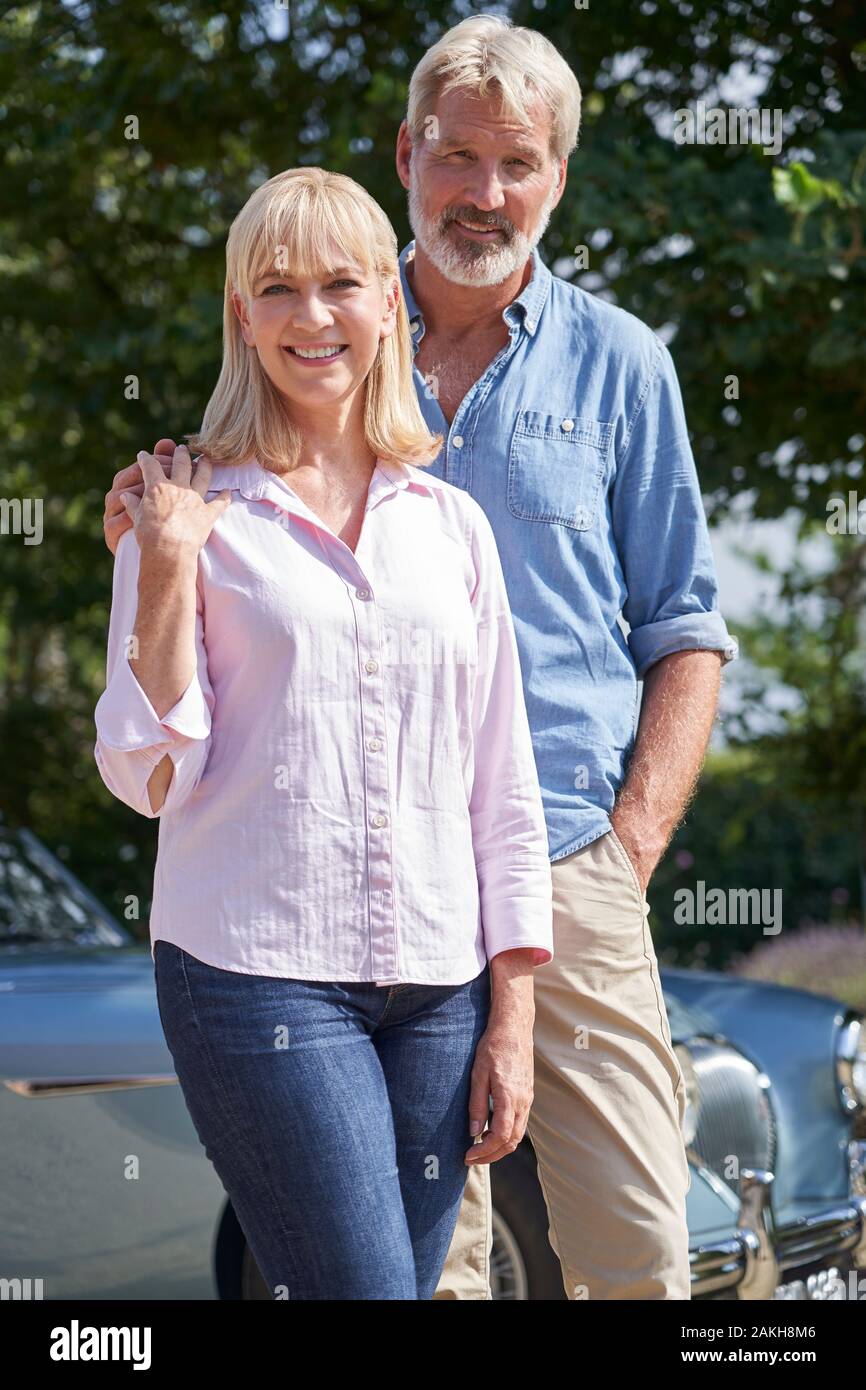 Portrait Of Mature Couple Standing Next To Classic Open Top Sports Car Stock Photo