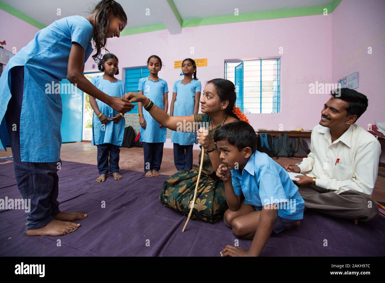 CAPTION: While Cluster Resource Person (CRP) Basavaraju observes, Sunithamma leads her primary school class in enacting a skit called 'Grandmother’s P Stock Photo