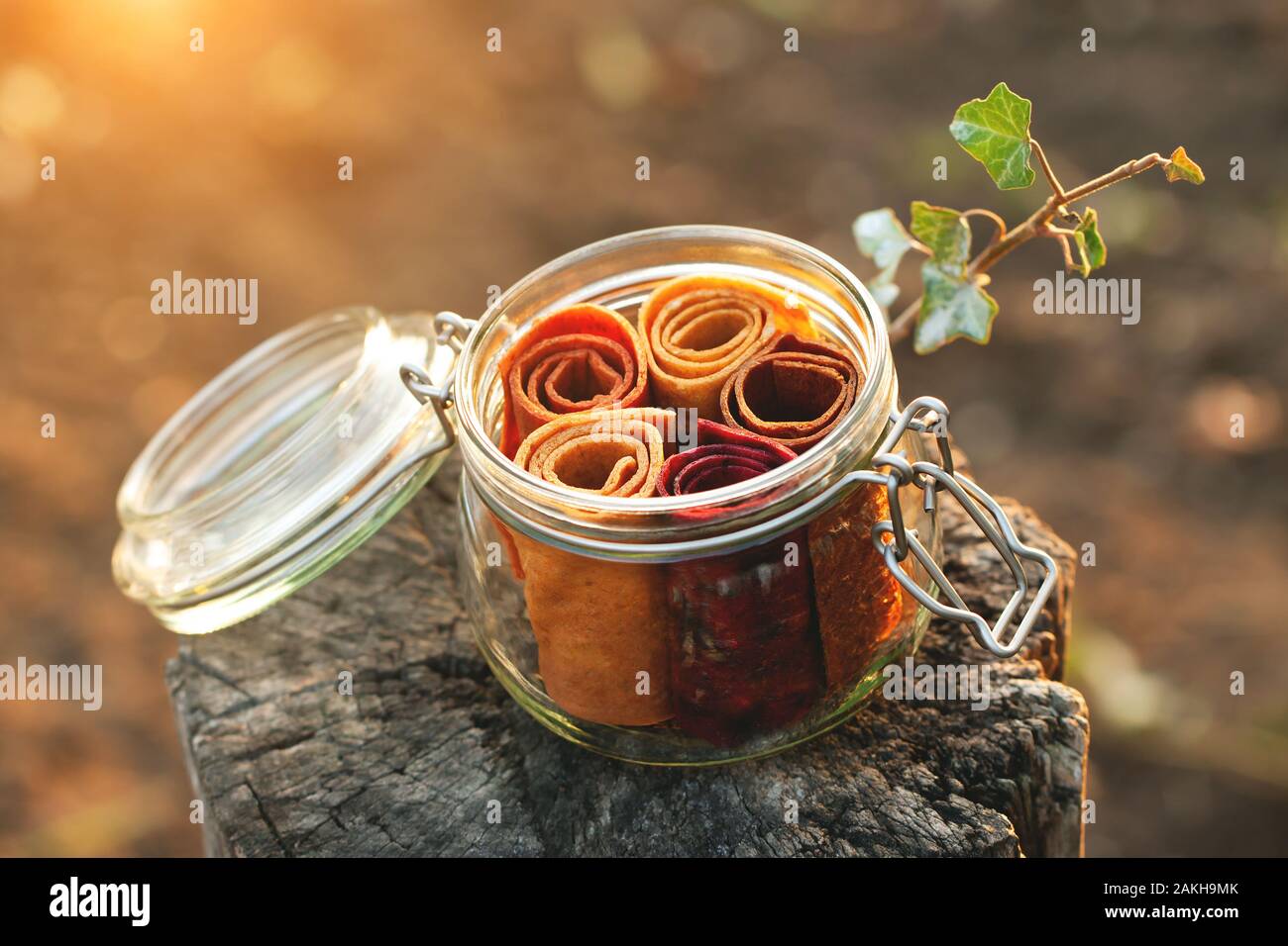 Glass jar with fruit pastille roll-up on a natural background. The concept of healthy organic sweets, proper nutrition, zero waste, vegan. Stock Photo