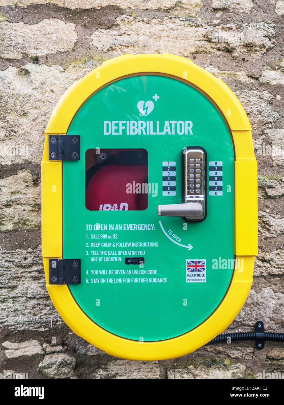 A modern public access defibrillator fixed to a stone wall. Stock Photo