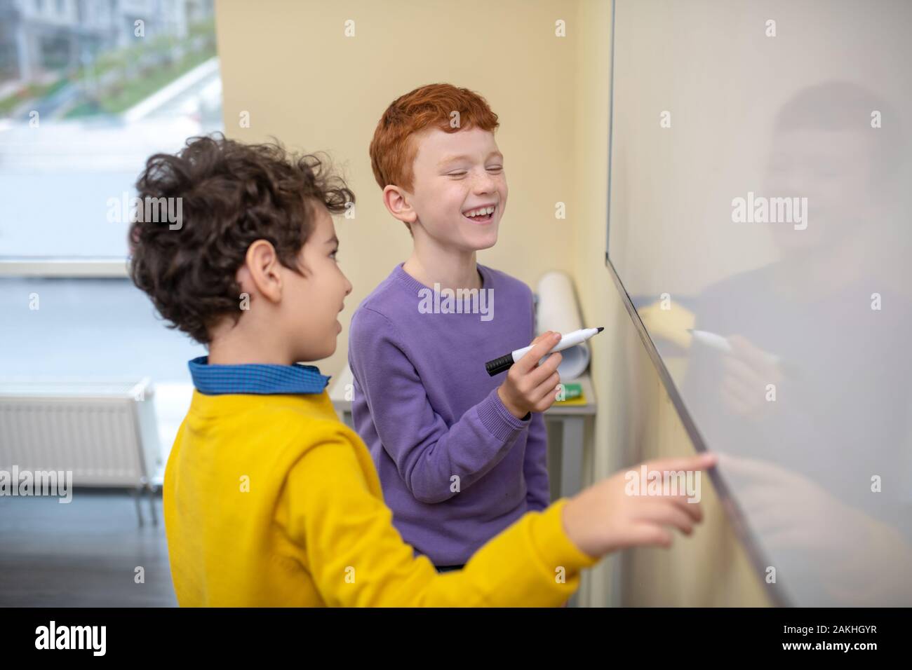 Two boys laughing and writing on the whiteboard Stock Photo - Alamy