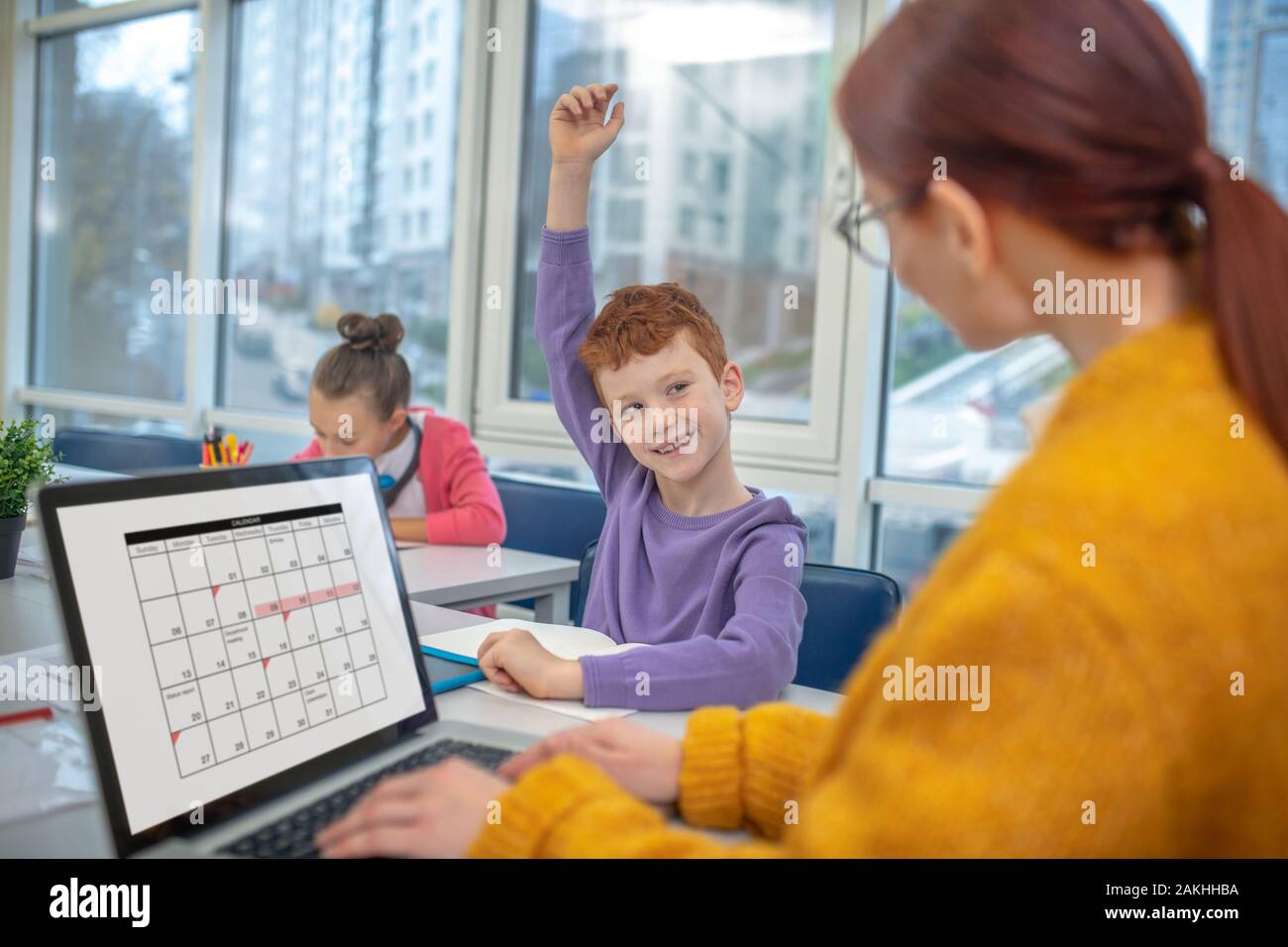 Schoolboy raising a hand to answer teachers question Stock Photo