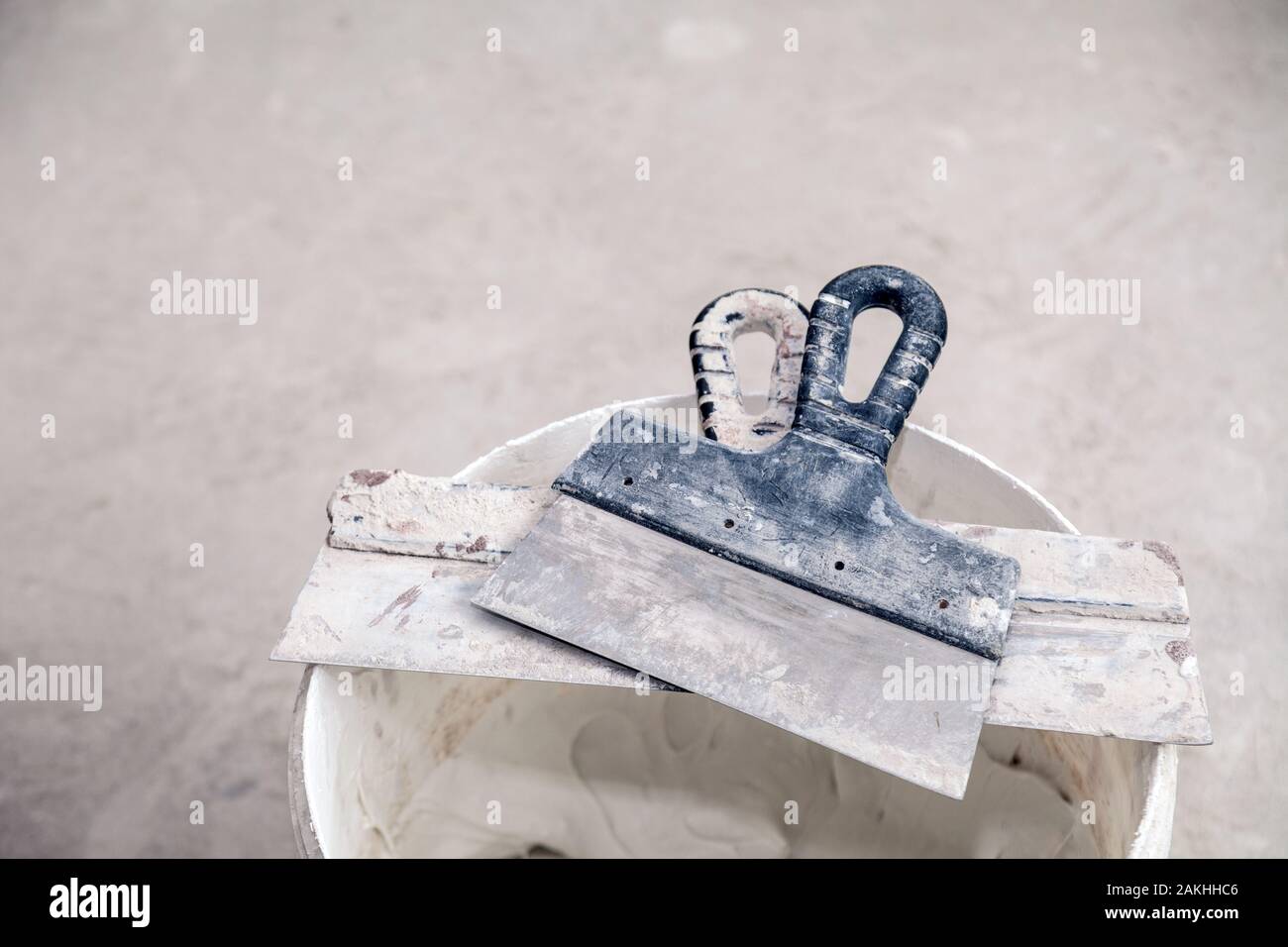 Decorative cement plaster and trowel in construction bucket ready for plastering. Spatula and a bucket of white putty. Top view Stock Photo
