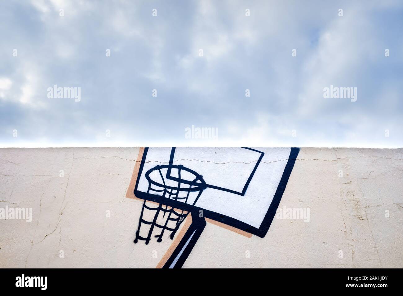 Outdoor basketball court decorated with street graffiti, half with blue