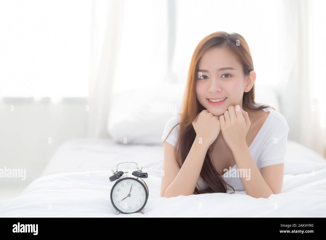 Beautiful of portrait young asian woman wake up in morning and alarm clock, girl standing hurry wake late with appointment with curtain background on Stock Photo