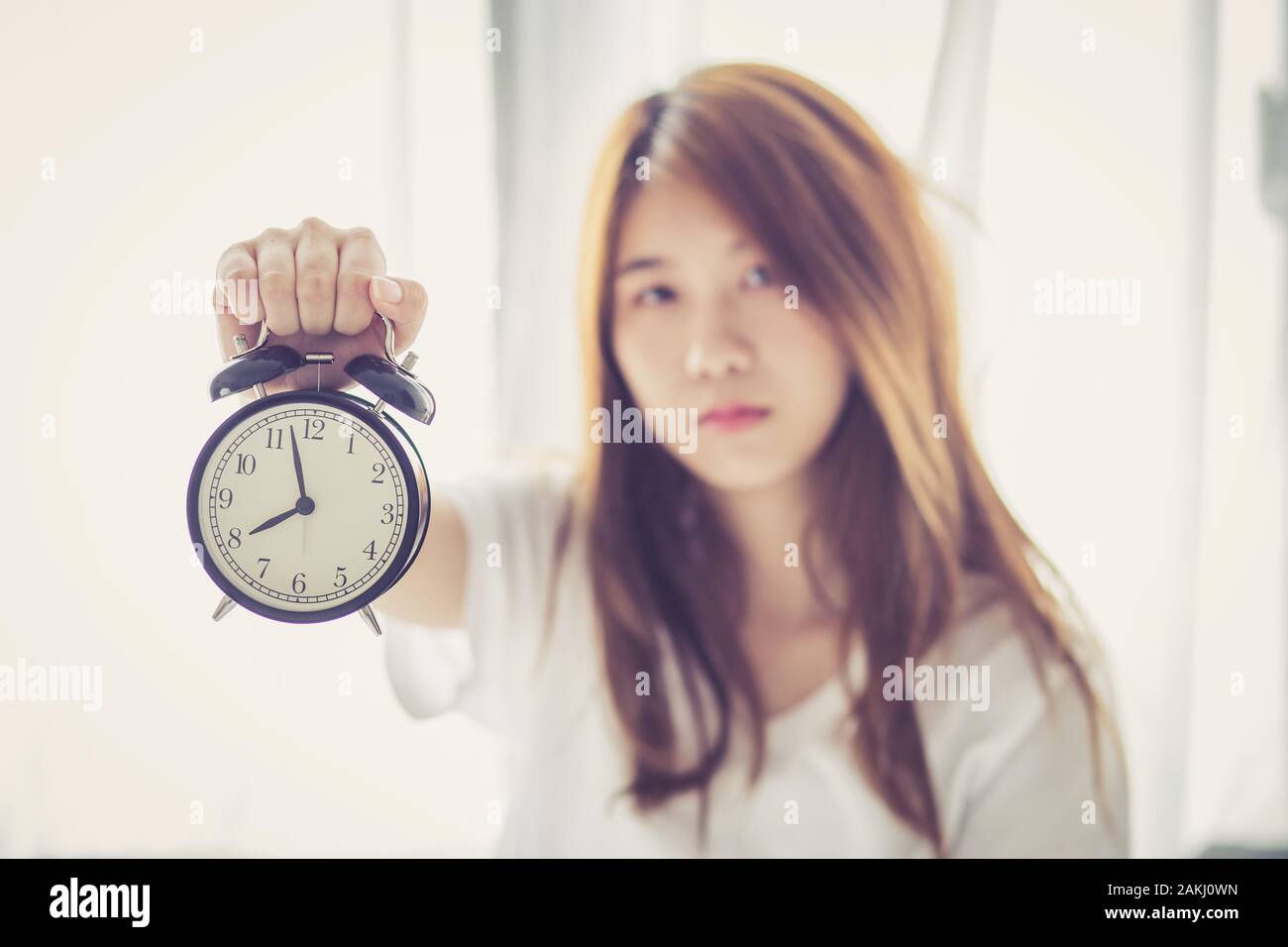 Beautiful asian young woman wake up in morning annoyed alarm clock holding hand, girl hurry wake late with appointment, lifestyle concept. Stock Photo
