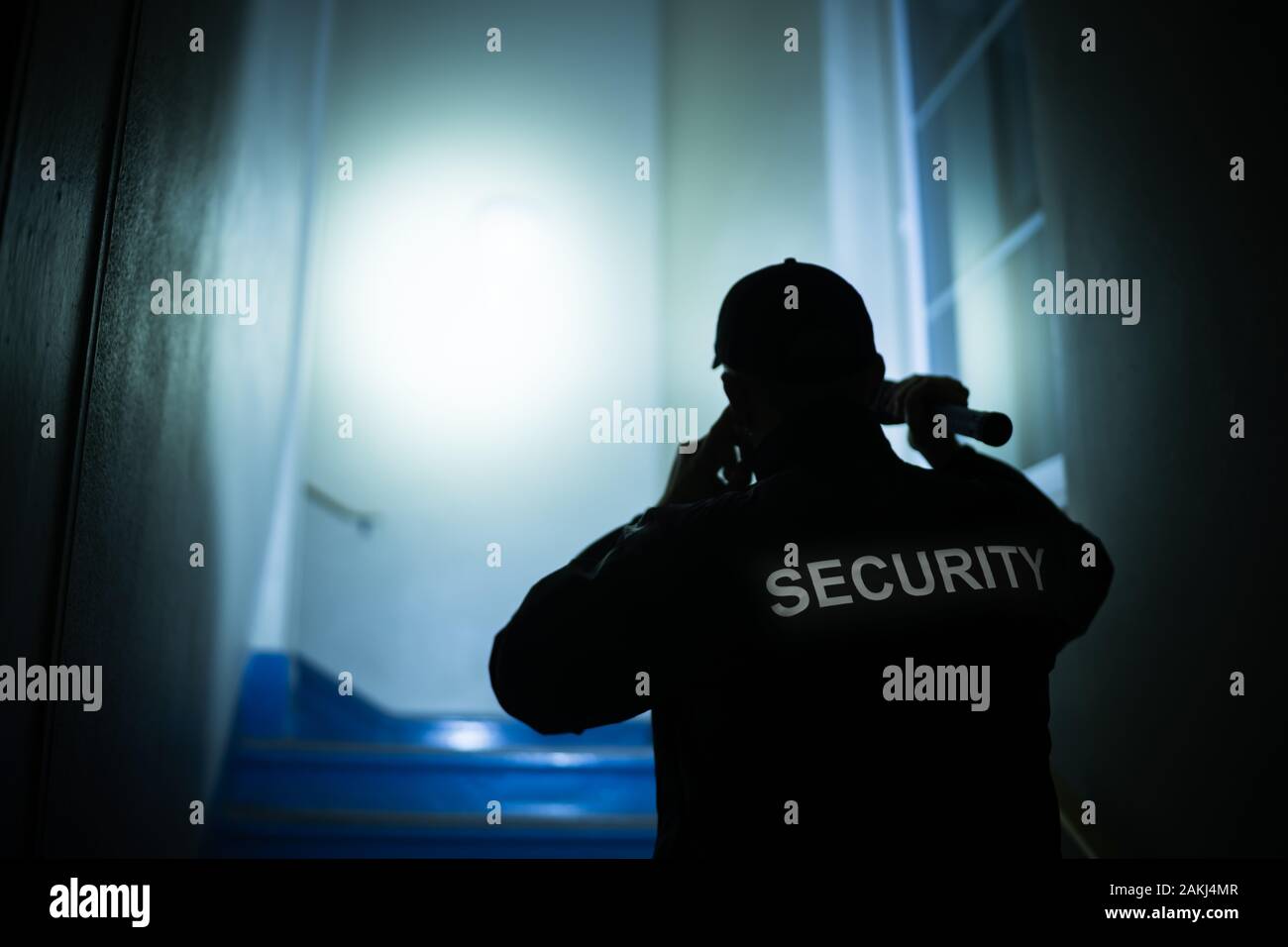 Security Guard Searching On Stairway With Flashlight Stock Photo