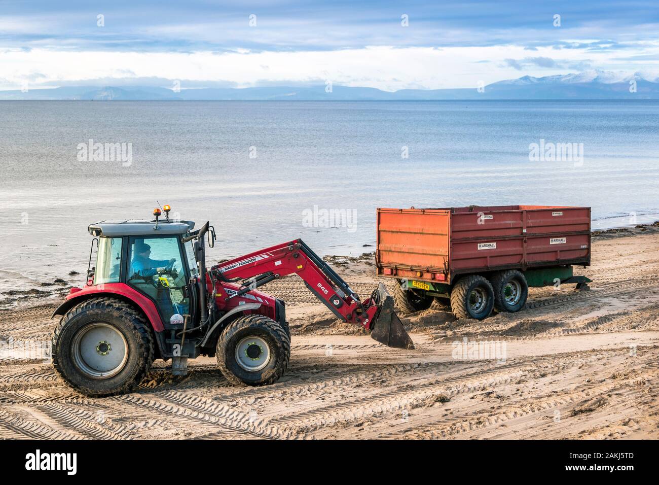 Tractor and trailer being used to clean the pollution and rubbish from the public beach, Irvine, North Ayrshire, UK Stock Photo