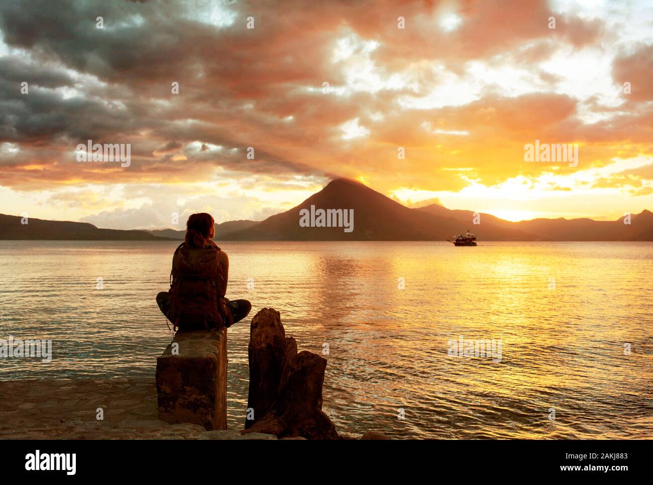Rear view of female backpacker looking at the beautiful sunset of Lake Atitlan, Panajachel, Guatemala. Dec 2018 Stock Photo
