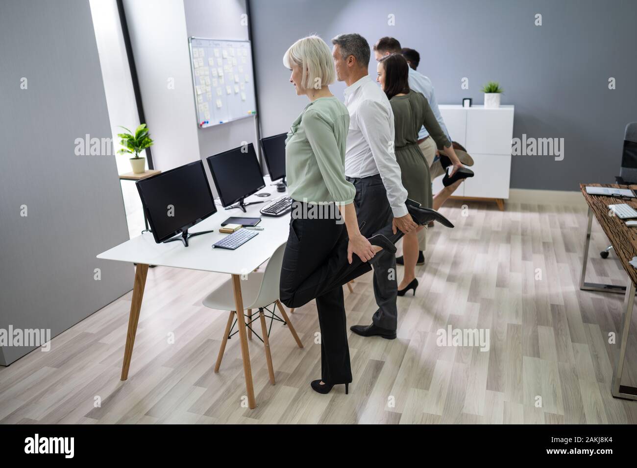Group Of Happy Young Businesspeople Doing Stretching Exercise In Office Stock Photo