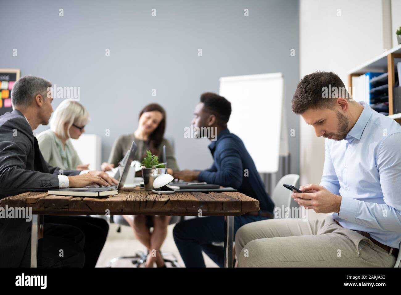 Distracted Businessman Using Mobile Phone In Meeting Stock Photo