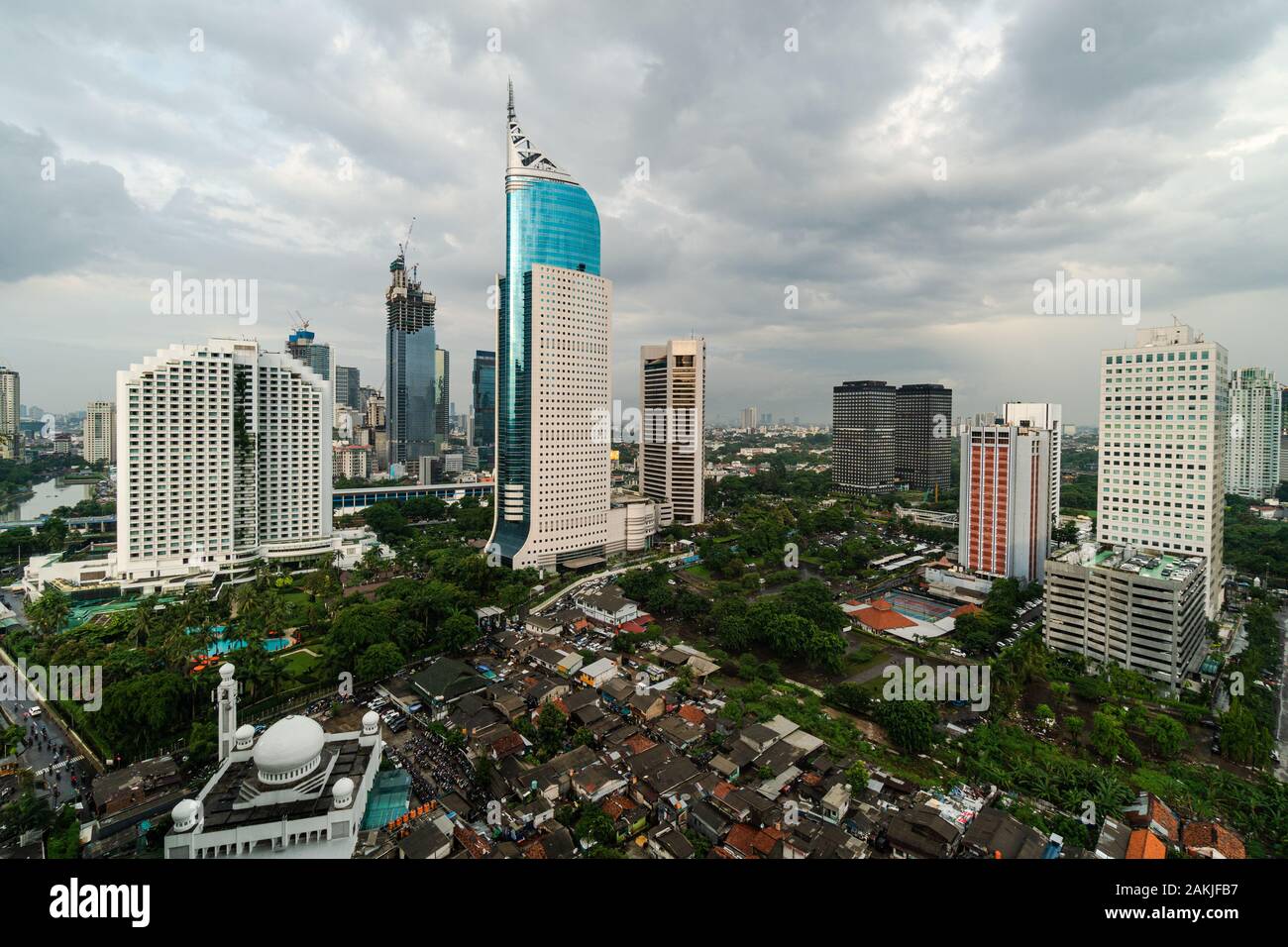 Dramatic sky over Jakarta downtown skyline where modern skyscrapers contrasts with poor residential district in Indonesia capital city Stock Photo
