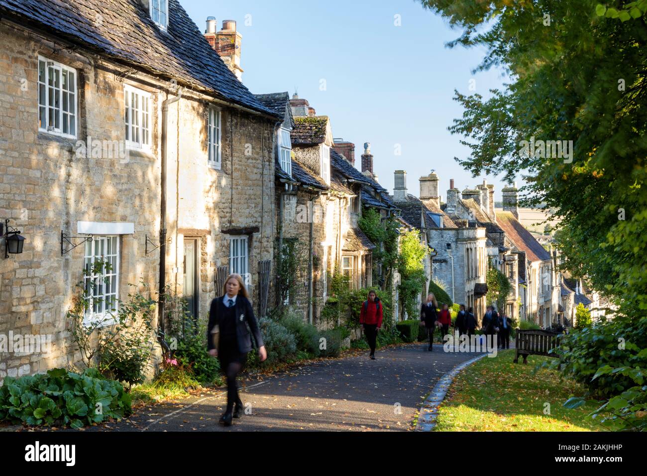 School children walking up The Hill to school past rows of homes in Burford, Oxfordshire, England, UK Stock Photo