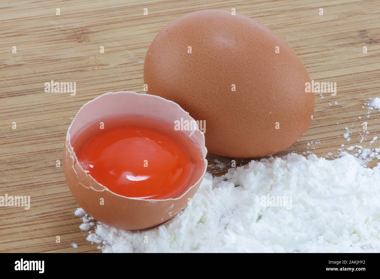 Two eggs and flour on a wood surface Stock Photo
