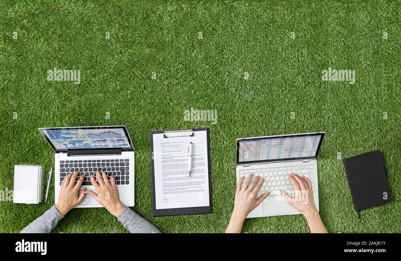 Overhead View Of Businesspeople's Hands On Grass With Laptops Working Stock Photo