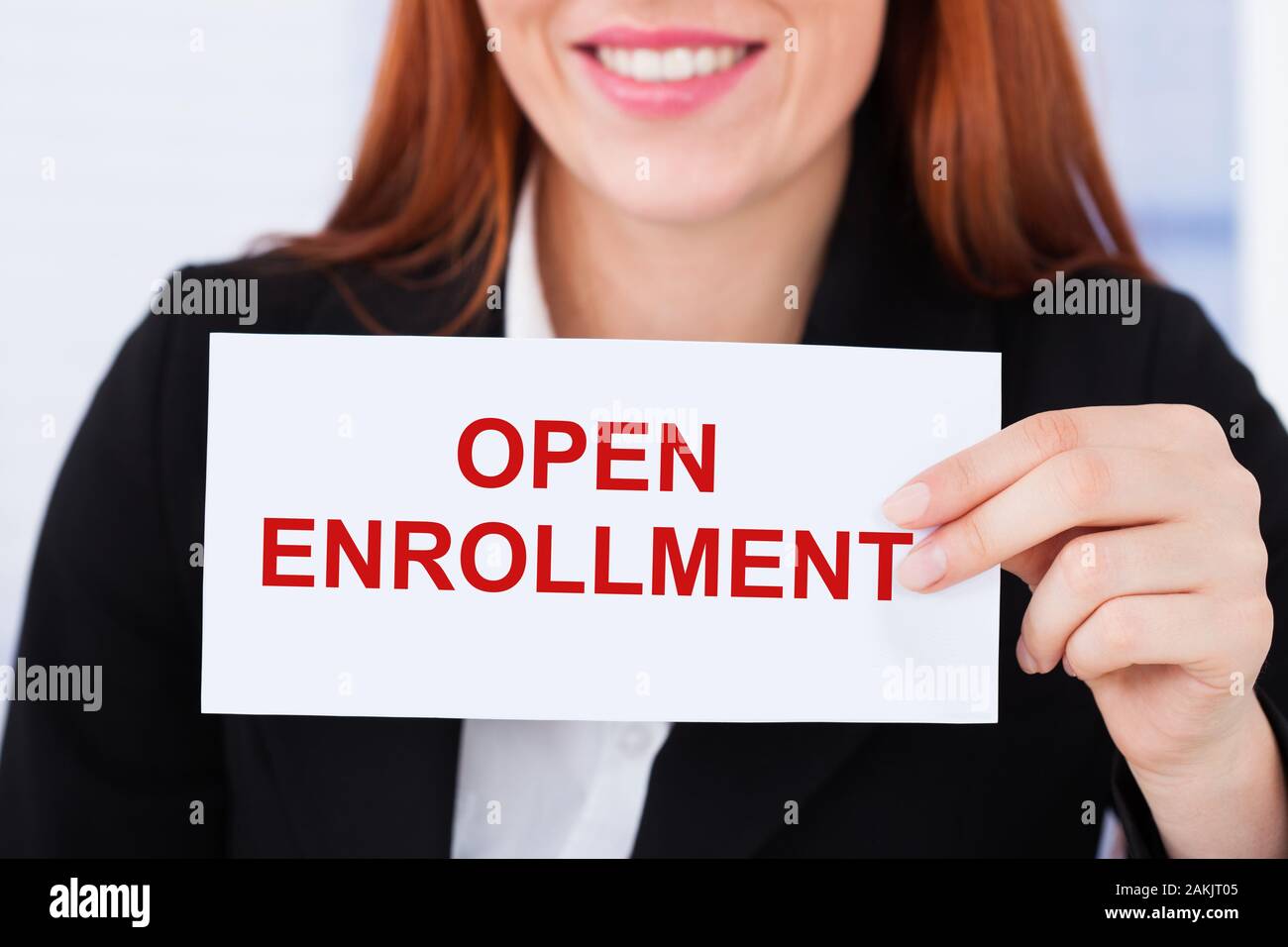 Smiling Businesswoman Holding Card With Open Enrollment Text In Hand Stock Photo