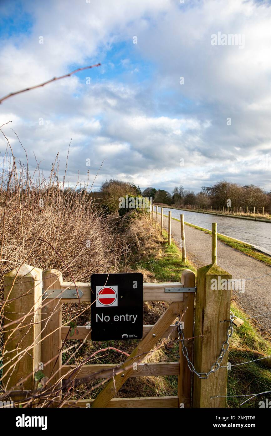 No entry, Canal and River Trust sign on locked gate next to Shropshire and Union Canal with towpath in Cheshire UK Stock Photo