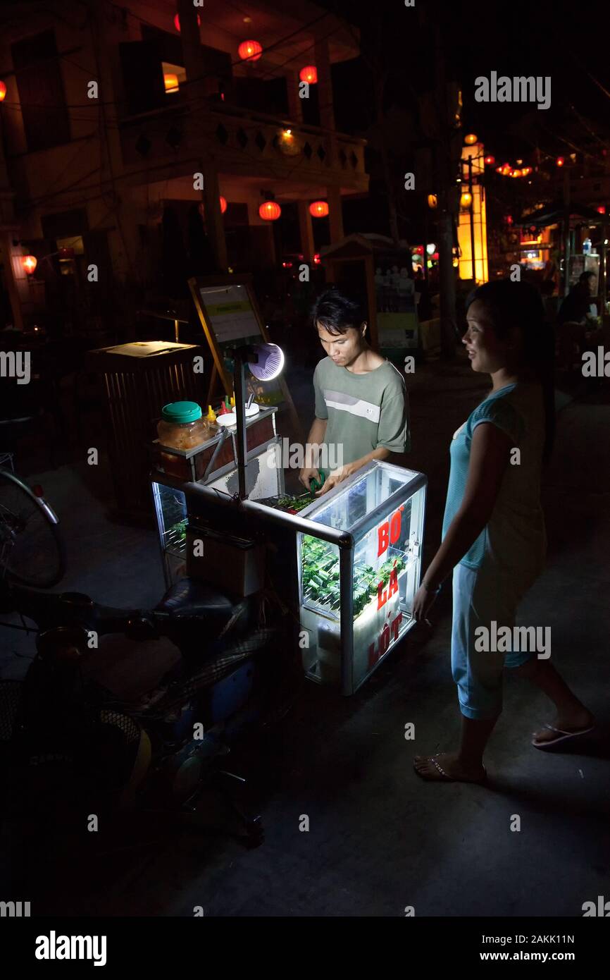 Asian street vendor with food stall at night. Trolley on wheels with snack,  sells street food in Vietnam. Stock Photo