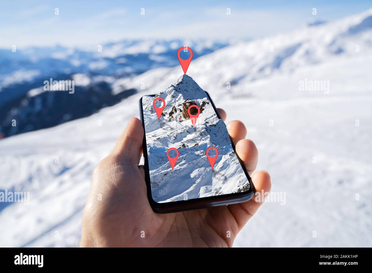 Person's Hand Holding Mobile Phone With Mountain Map Against Blurred Snowy Background Stock Photo