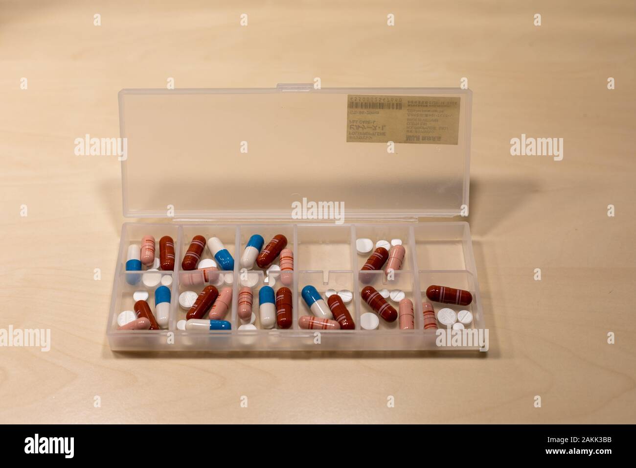 Plastic pill organizer with pills, tablets and capsules on a birch table Stock Photo