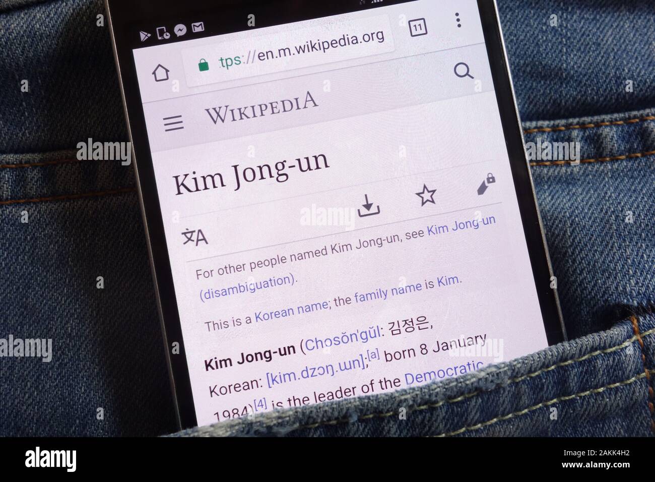Informations about Kim Jong-un on Wikipedia website displayed on smartphone hidden in jeans pocket Stock Photo