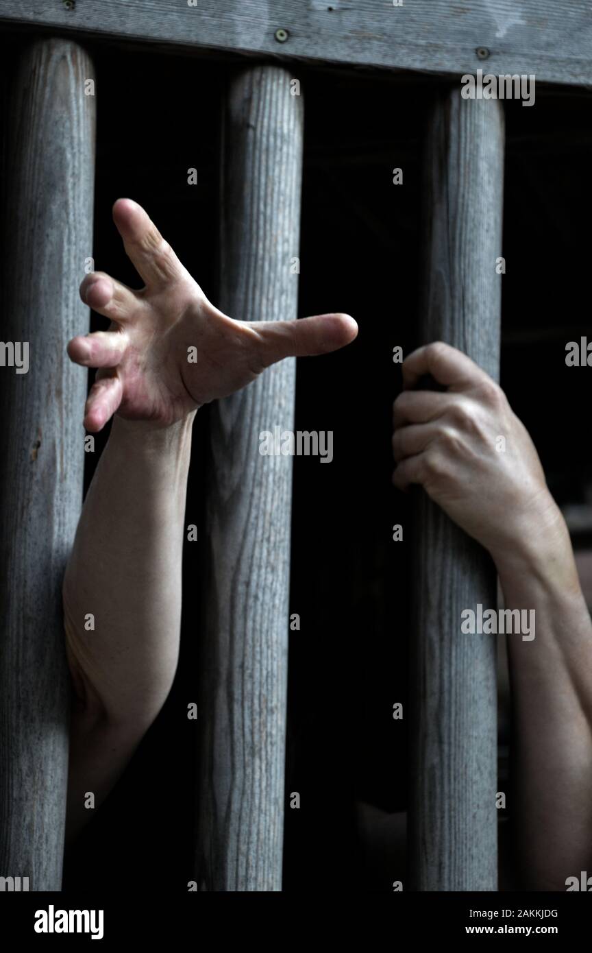 prisoner behind wooden bars begging for help Stock Photo